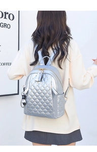 Detail of silver quilted PU leather backpack with gold rivets and black cat plush charm