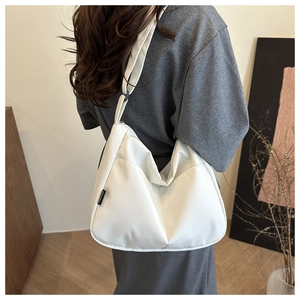 Close-up of white crescent canvas crossbody bag with adjustable strap and logo detail