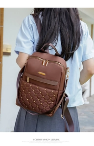 Close-up of quilted brown nylon backpack with gold rivets and smooth zipper detail