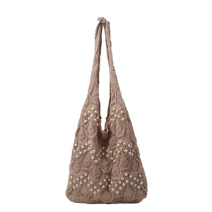 Sac fourre-tout marron en tricot avec perles décoratives sur fond blanc neutre