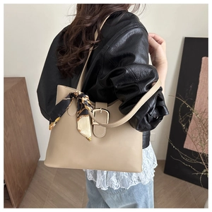 Detail of a large beige tote bag with a decorative silk scarf tied on the shoulder strap