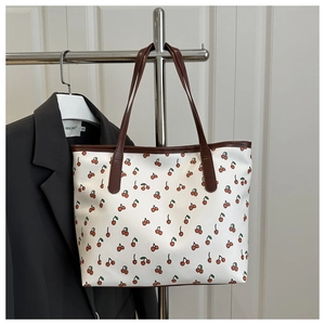 Détail du sac cabas blanc avec imprimés cerises et anses en cuir marron
