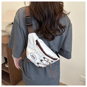 Détail du sac de poitrine en toile blanche avec étiquette mode et bandoulière réglable