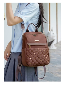Detail of coffee brown quilted nylon backpack with gold studs and brand logo plate