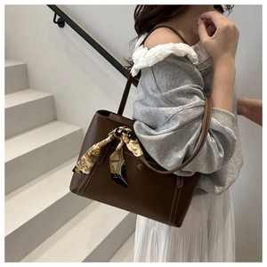 Detail of a brown tote bag with decorative silk scarf and contrast stitching accents