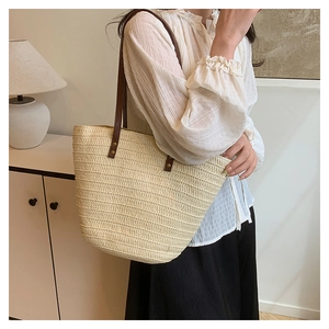 Gros plan du sac fourre-tout en paille tissée avec texture beige et anses en cuir brun
