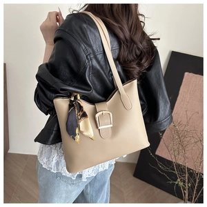 Detail of large beige tote bag with vintage silk scarf on handle worn with black leather jacket