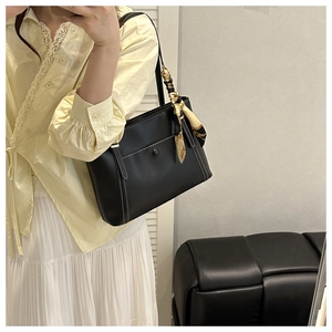 Detail of black faux leather tote bag with contrast stitching and decorative silk scarf