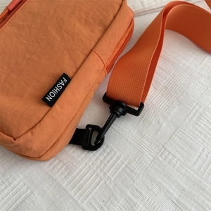 Bolso bandolera minimalista de nailon naranja con textura impermeable y etiqueta