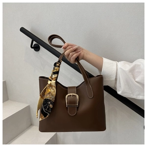 Brown leather tote bag featuring a gold metal buckle and decorative floral silk scarf