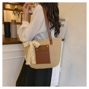 Detail of straw tote bag with brown leather pocket and large beige lace bow decoration