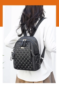 Detail of black quilted leather backpack featuring gold rivets and dual zipper closure
