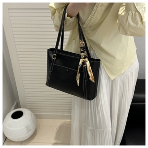 Close-up of black PU leather tote bag featuring contrast stitching and a silk scarf handle
