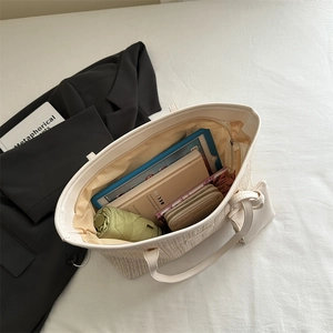 Grand sac cabas en paille beige avec bandoulière montrant le rangement interne et la pochette