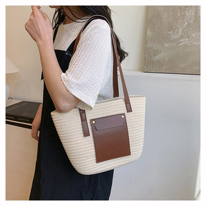 Detail of woven straw tote bag with brown leather pocket and golden rivets for women