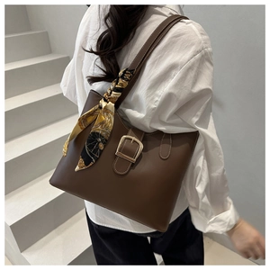 Detail of brown leather tote bag with elegant floral scarf wrap and gold buckle