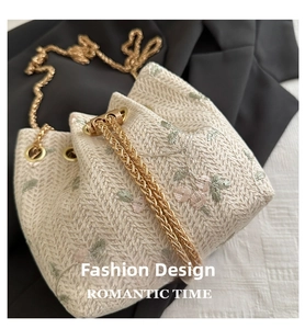 Close-up of woven bucket bag featuring pink flower embroidery and pearl drawstring detail