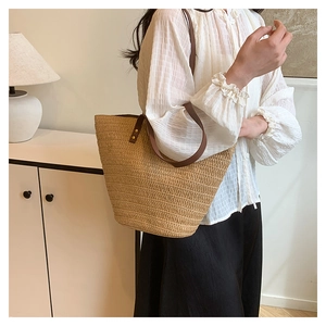 Détail du sac cabas en paille avec anses en cuir marron et rivets dorés
