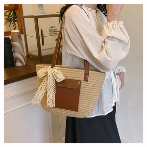 Detail of beige woven tote bag with brown leather pocket and white lace bow decoration