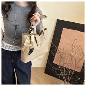 Detailed view of beige tote bag with white stitching and decorative silk scarf on handle