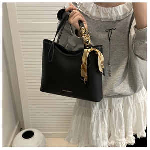 Detail of black tote bag with white contrast stitching and printed silk scarf handle