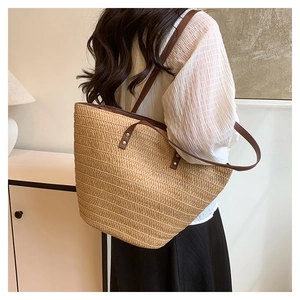 Back view of model carrying a large straw tote bag with brown straps in a minimalist room