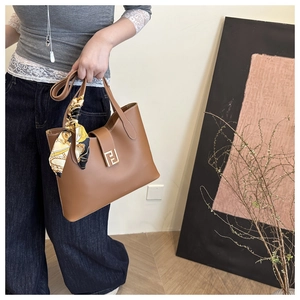 Detail of a brown leather bucket bag with a golden FF clasp and floral handle scarf decoration
