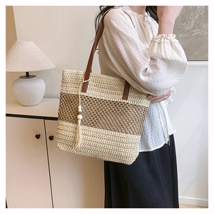 Detail of woven beach tote showing beige and brown stripes with tassel and wood bead charm