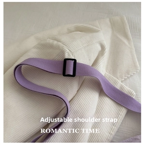 Detail of adjustable purple woven shoulder strap with black buckle on canvas bag