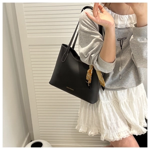 Détail du cabas noir avec surpiqûres blanches contrastées et accessoire en foulard de soie