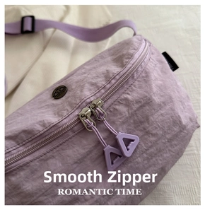 Detail of lavender purple pleated nylon bag featuring smooth dual metal zippers and tags