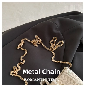 Close-up of the elegant gold metal chain strap on a woven crossbody bag texture