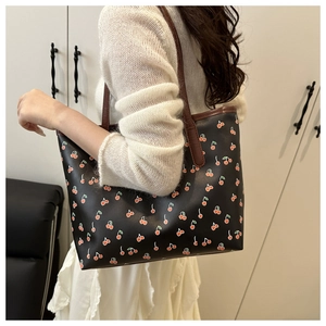 Vue détaillée d'un sac cabas noir à motifs cerises avec des fines bandoulières marron