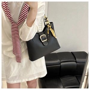 Detail of black leather tote bag with gold horseshoe buckle and floral silk scarf accessory