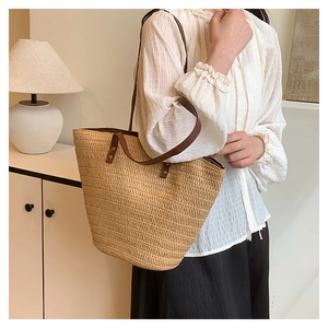 Detail of straw tote bag showing natural woven texture and brown leather handle