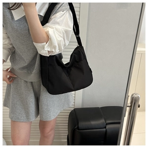 Minimalist black nylon bucket bag shown being worn as a crossbody bag for daily use