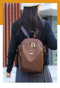 Détail d'un sac à dos marron en Oxford avec logo doré et ornements étoiles en métal