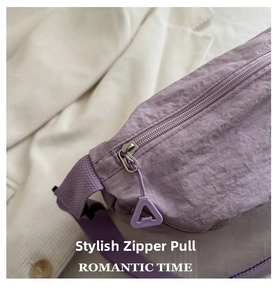 Detail of silver metal zipper with purple triangular puller on nylon crossbody bag