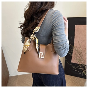 Detail of caramel leather tote bag featuring a gold F-logo buckle and printed silk scarf