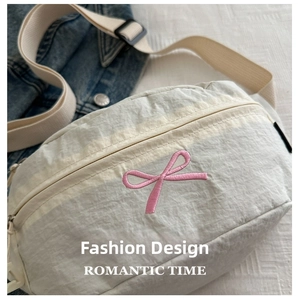 Macro detail of butterfly ribbon embroidery on a cream nylon crossbody sports bag