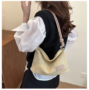 Dettaglio borsa tote in paglia intrecciata beige con tracolla in pelle e logo impresso