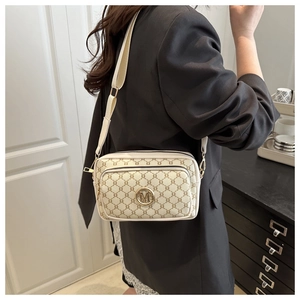 Detail of creamy small square bag with brown monogram pattern and golden M logo