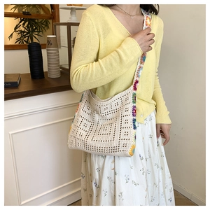 Detail view of crochet shoulder bag with colorful floral strap and cream knit texture