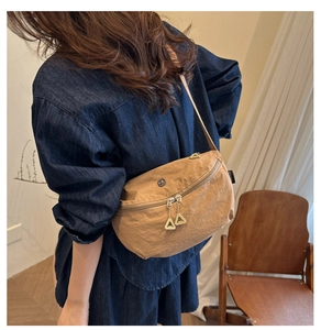 Detail of khaki nylon crescent crossbody bag featuring dual zippers and metal logo