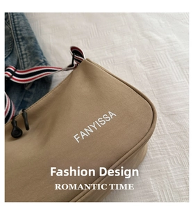 Gros plan du sac kaki avec texte FANYISSA et bandoulière rayée rouge blanc et bleu