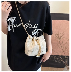 Detailed side view of lace straw bucket bag with floral embroidery and pearl charms