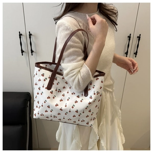 Detail of cherry print tote bag with brown leather straps and spacious canvas interior