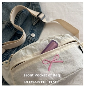 Detail showing the front zipper pocket on white crescent bag with pink bow embroidery