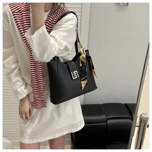 Detail of black leather bucket bag with gold geometric clasp and floral silk scarf accessory