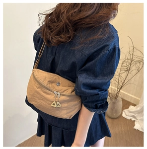 Detail of tan nylon crossbody bag with dual zippers and signature metal pullers